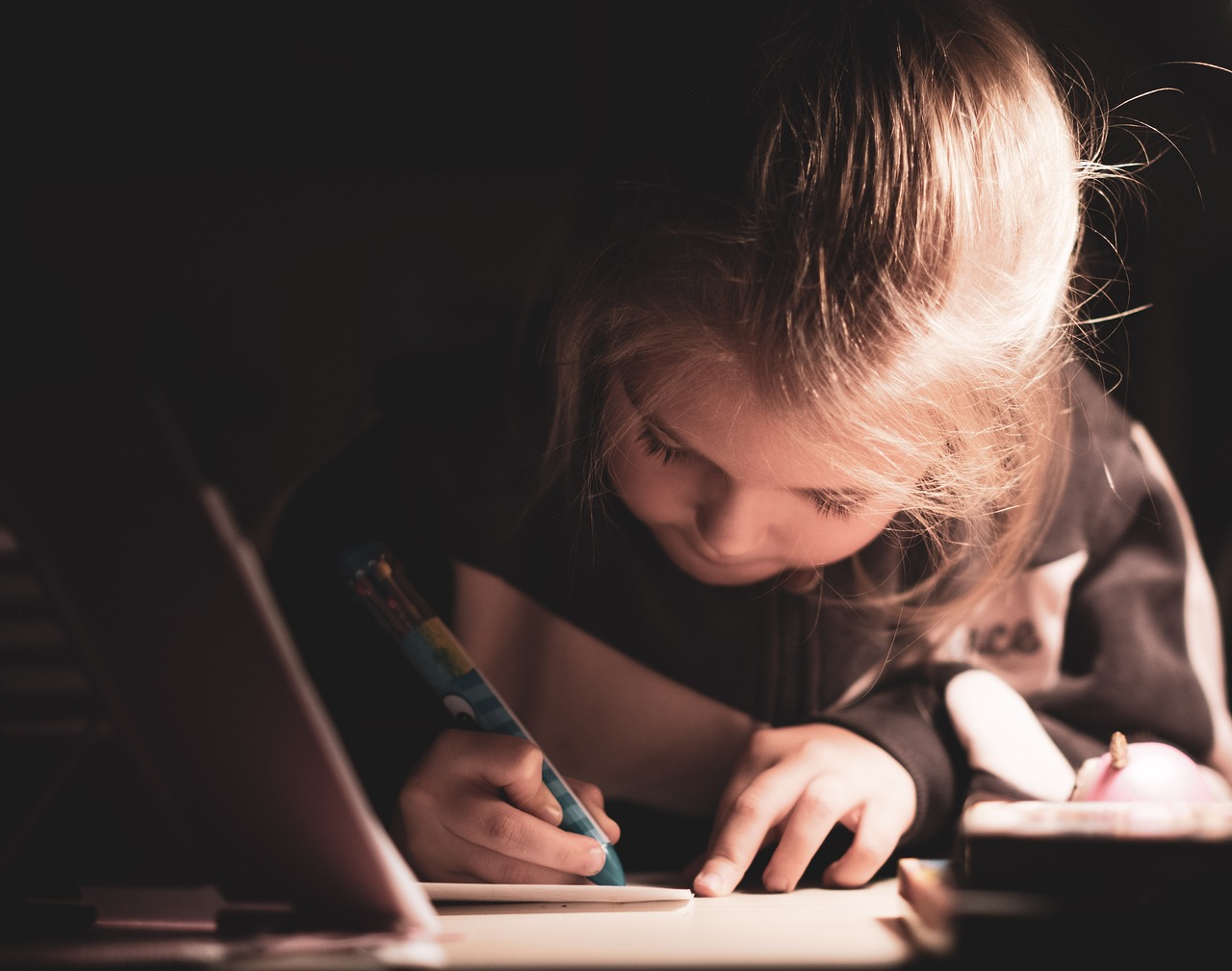 zdjęcie dziewczynki, która pisze w zeszycie piórem kulkowym